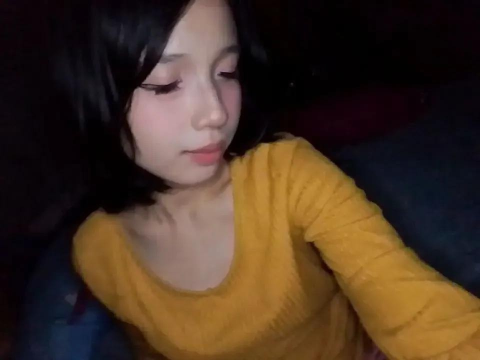 Yarin in a mustard yellow sweater, resting with her black hair framing her face